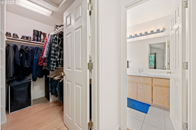 spacious closet with a sink and light wood-style flooring