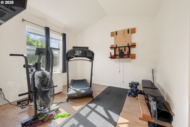 exercise area featuring baseboards, wood finished floors, and lofted ceiling