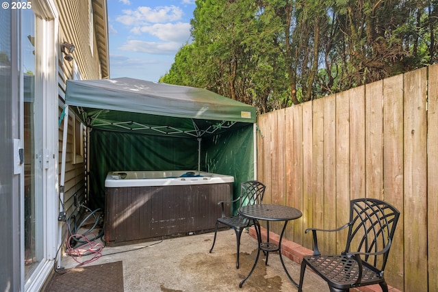 view of patio / terrace featuring a hot tub, fence, and cooling unit