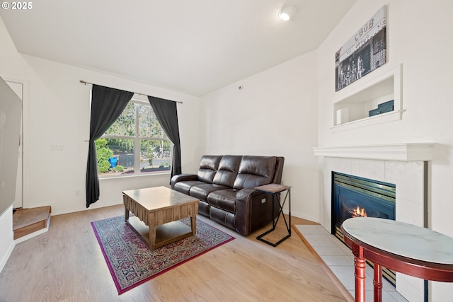 living area with baseboards, a fireplace, and wood finished floors