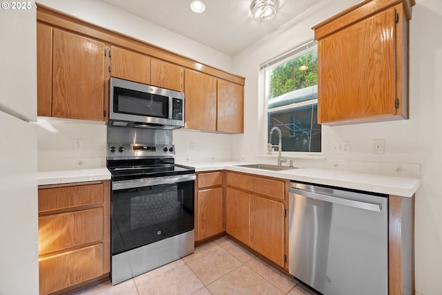 kitchen with light countertops, a sink, light tile patterned floors, and stainless steel appliances