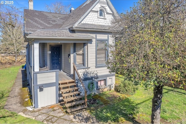 view of front of house featuring a shingled roof, a chimney, and a front yard