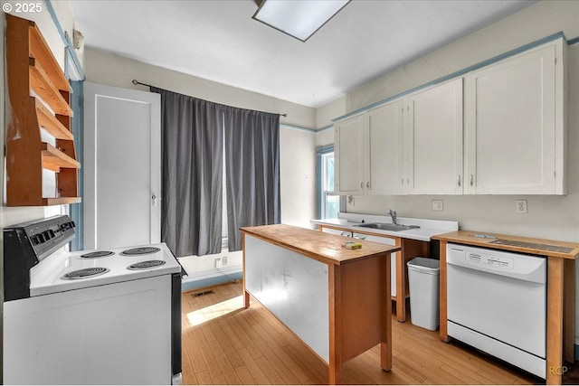 kitchen with white appliances, white cabinets, a sink, and light wood-style flooring