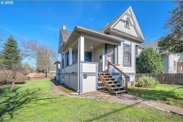 view of front facade featuring a chimney, a front yard, and fence