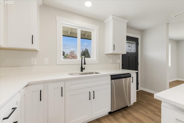 kitchen with visible vents, dishwasher, a sink, white cabinets, and light wood-style flooring
