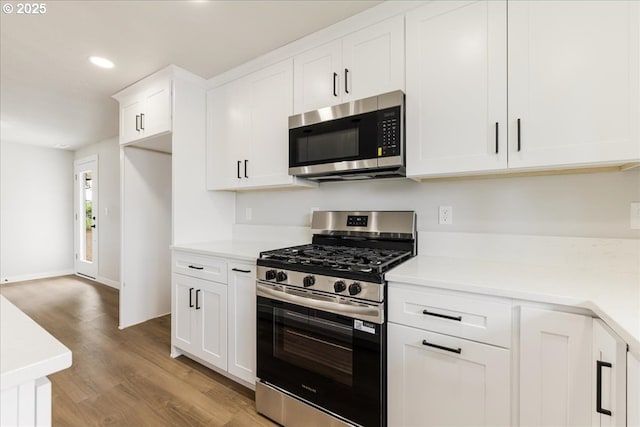 kitchen featuring appliances with stainless steel finishes, light wood-type flooring, light countertops, white cabinets, and recessed lighting