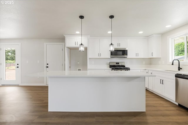 kitchen featuring a kitchen island, white cabinets, appliances with stainless steel finishes, and a sink