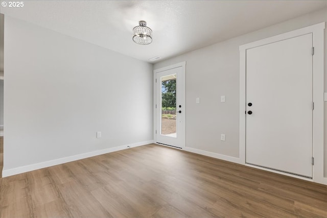 unfurnished room featuring baseboards, a chandelier, and light wood-type flooring