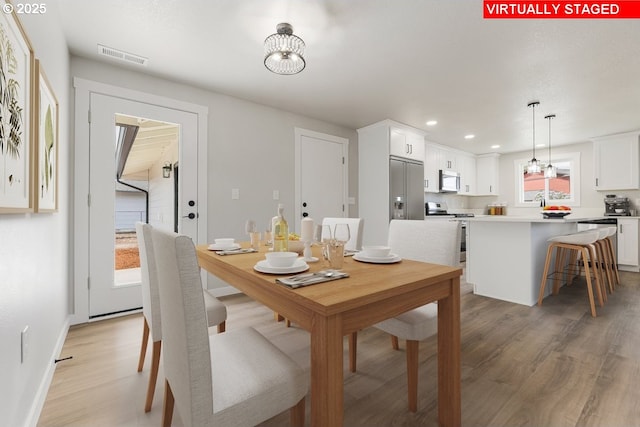dining room with visible vents, recessed lighting, light wood-style floors, and a notable chandelier