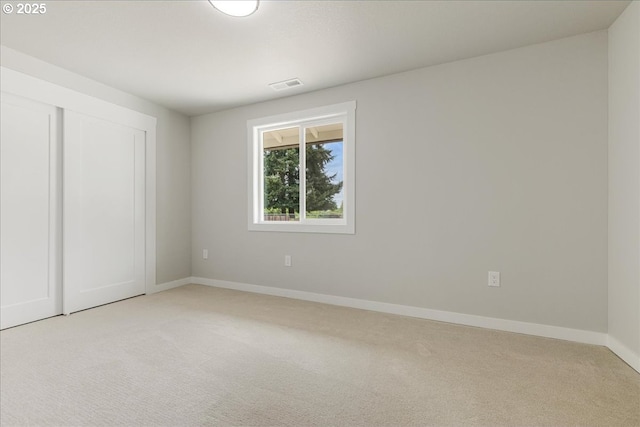 unfurnished bedroom featuring baseboards, visible vents, light carpet, and a closet