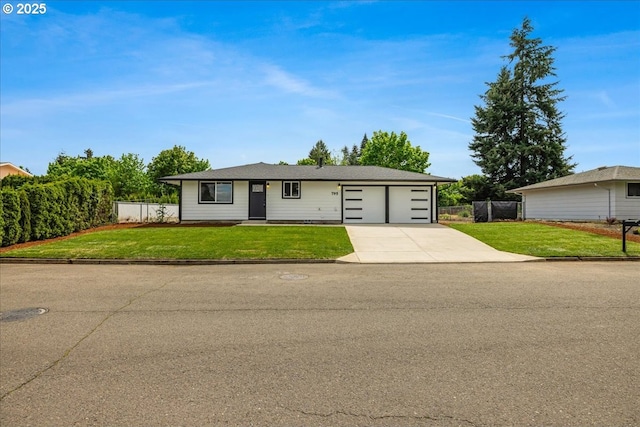 ranch-style house with an attached garage, fence, driveway, and a front lawn