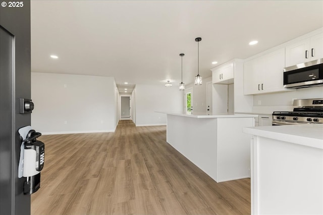 kitchen with white cabinets, stainless steel appliances, open floor plan, and light wood finished floors