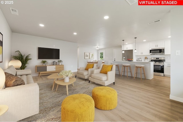 living area with recessed lighting, visible vents, and light wood-type flooring