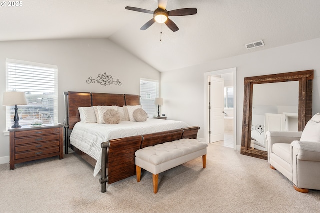 bedroom with ceiling fan, ensuite bath, vaulted ceiling, and light carpet