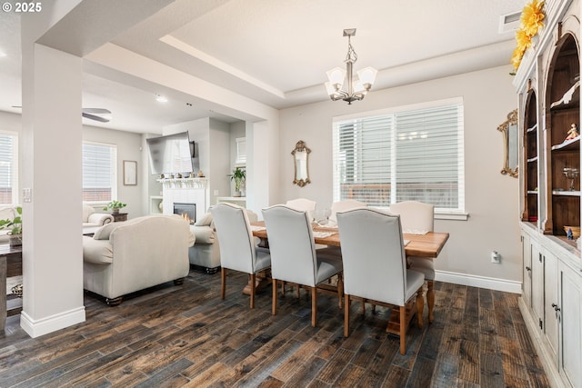 dining area featuring dark wood-type flooring, a raised ceiling, and a notable chandelier