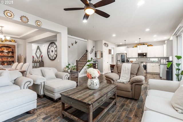 living room with ceiling fan with notable chandelier, sink, and dark wood-type flooring