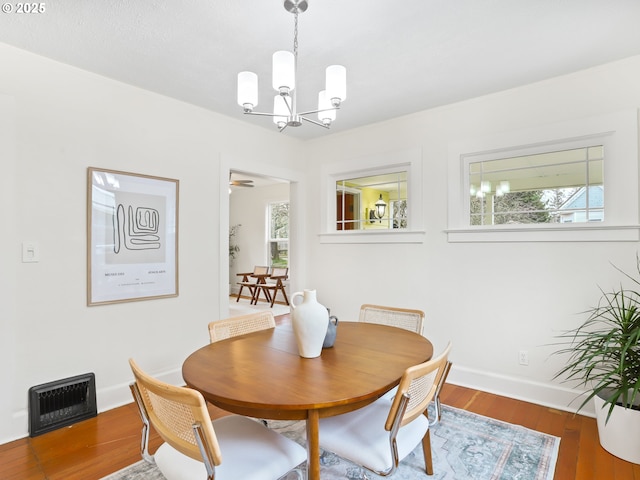 dining area with hardwood / wood-style flooring and a notable chandelier