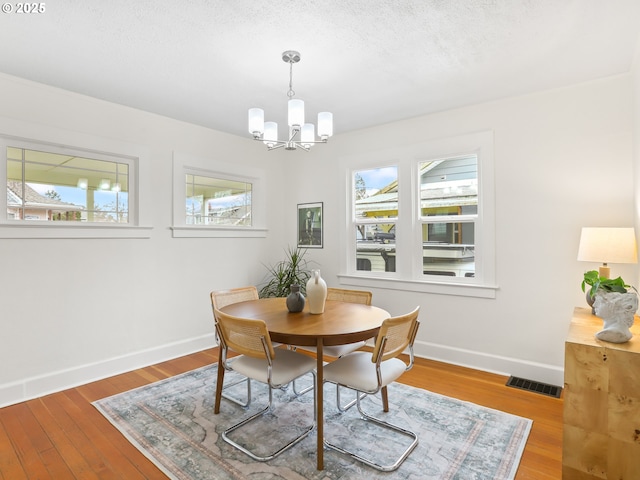 dining area featuring hardwood / wood-style flooring, a chandelier, and a textured ceiling