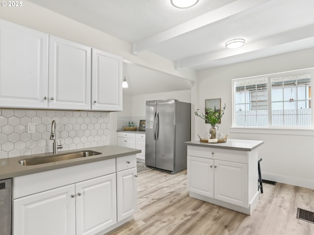 kitchen featuring light wood-type flooring, sink, appliances with stainless steel finishes, white cabinets, and decorative backsplash