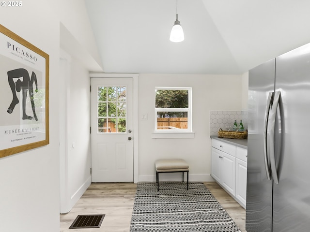 doorway featuring vaulted ceiling and light hardwood / wood-style flooring