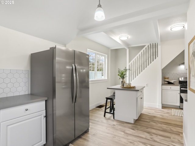 kitchen featuring appliances with stainless steel finishes, white cabinets, decorative light fixtures, light hardwood / wood-style floors, and a breakfast bar