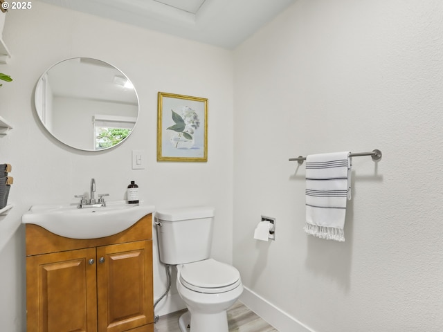 bathroom with hardwood / wood-style flooring, toilet, and vanity