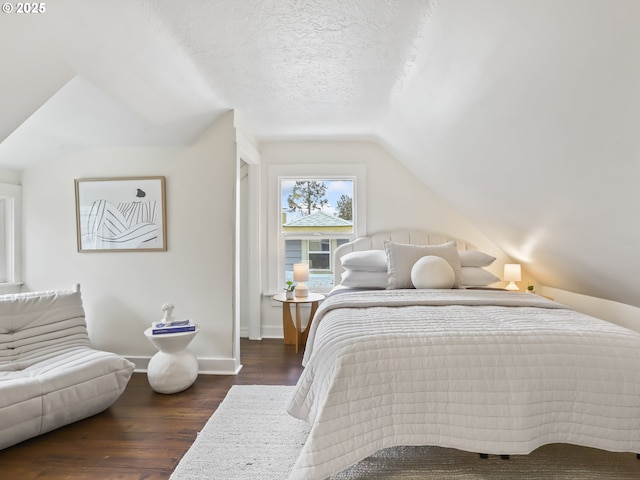 bedroom with a textured ceiling, dark wood-type flooring, and vaulted ceiling