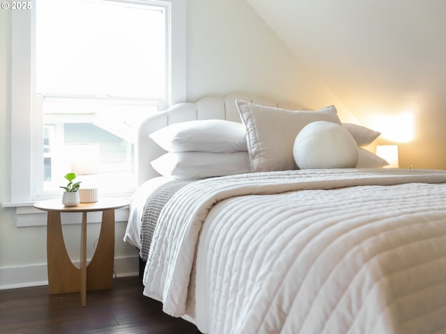 bedroom with multiple windows, vaulted ceiling, and dark hardwood / wood-style flooring