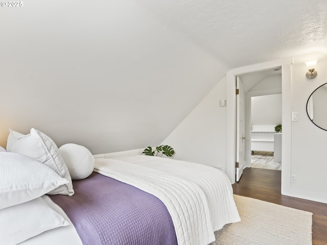 bedroom featuring a textured ceiling, vaulted ceiling, and dark hardwood / wood-style flooring