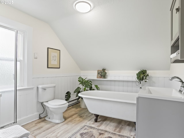 bathroom featuring a bathtub, toilet, vaulted ceiling, vanity, and hardwood / wood-style floors