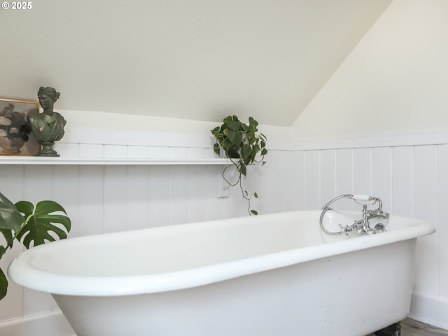 bathroom featuring vaulted ceiling and a washtub