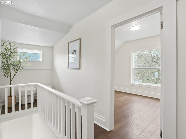 hall featuring vaulted ceiling, dark wood-type flooring, and a textured ceiling