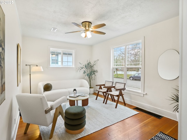 living room with hardwood / wood-style flooring, plenty of natural light, a textured ceiling, and ceiling fan