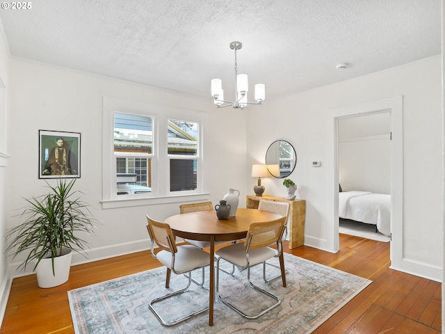 dining space with a textured ceiling, a chandelier, and wood-type flooring