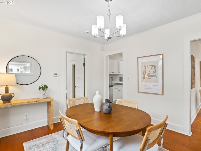 dining area featuring crown molding, wood-type flooring, a notable chandelier, and sink