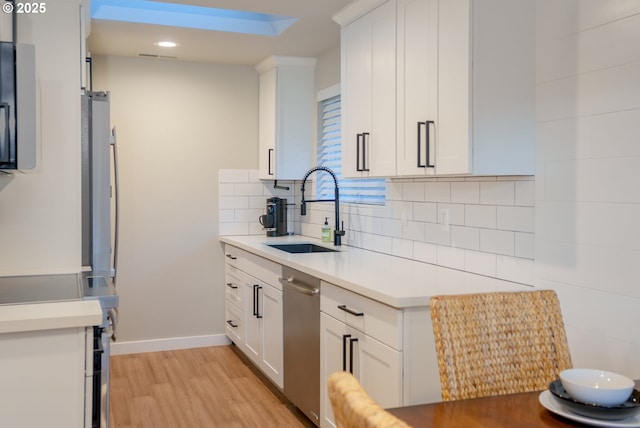 kitchen with a sink, light wood-style floors, tasteful backsplash, and light countertops