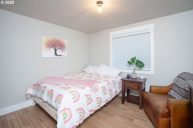 bedroom with baseboards, a textured ceiling, and wood finished floors