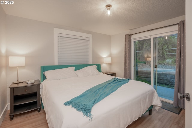 bedroom with a textured ceiling, wood finished floors, and access to outside