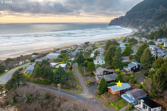 aerial view at dusk featuring a beach view, a water view, and a residential view