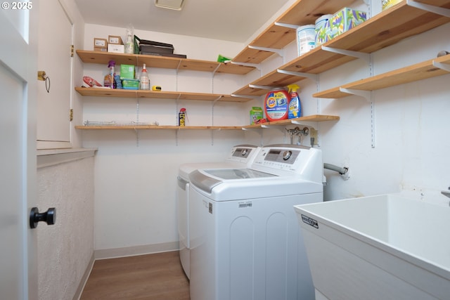 washroom with washing machine and clothes dryer, baseboards, laundry area, light wood-style floors, and a sink