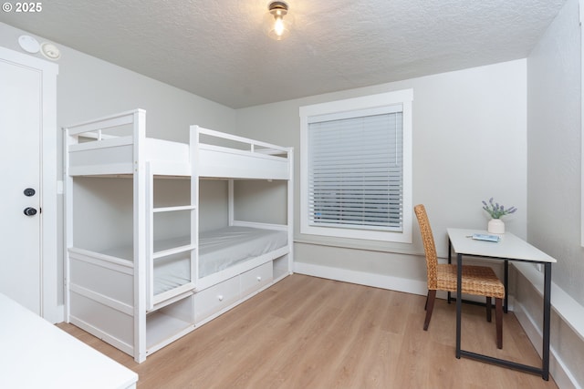 bedroom with baseboards, a textured ceiling, and wood finished floors