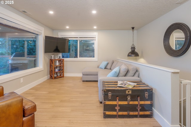 living room with wood finished floors, visible vents, and a textured ceiling