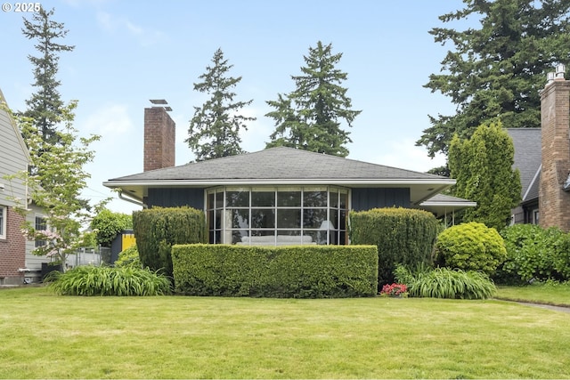 back of property with a chimney, a lawn, and board and batten siding