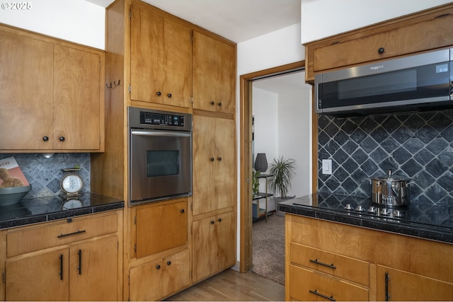 kitchen featuring stainless steel appliances, backsplash, light wood-style floors, and brown cabinets