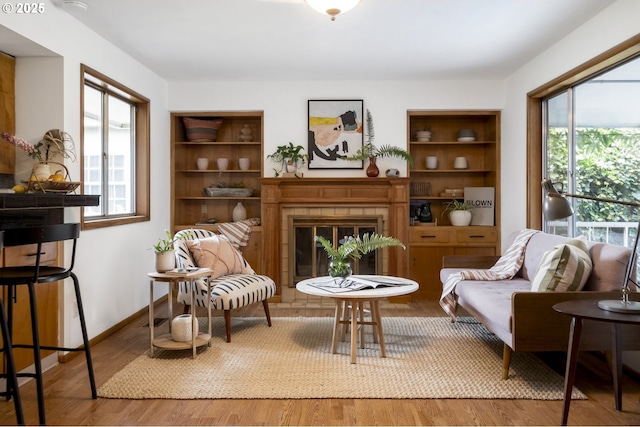 living area with a glass covered fireplace, plenty of natural light, and wood finished floors