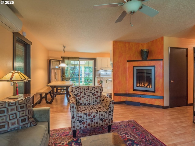17758 SE Washington St, Portland, OR 97233 - living area with a wall unit AC, light wood finished floors, a textured ceiling, a glass covered fireplace, and baseboards