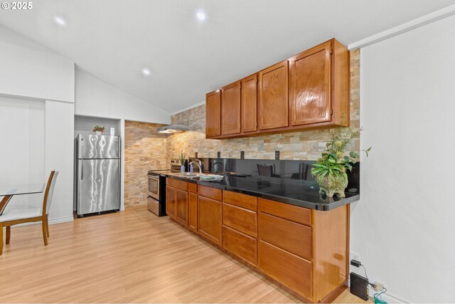 1000 S King St, Seaside, OR 97138 - kitchen featuring stainless steel appliances, vaulted ceiling, light wood finished floors, decorative backsplash, and brown cabinetry