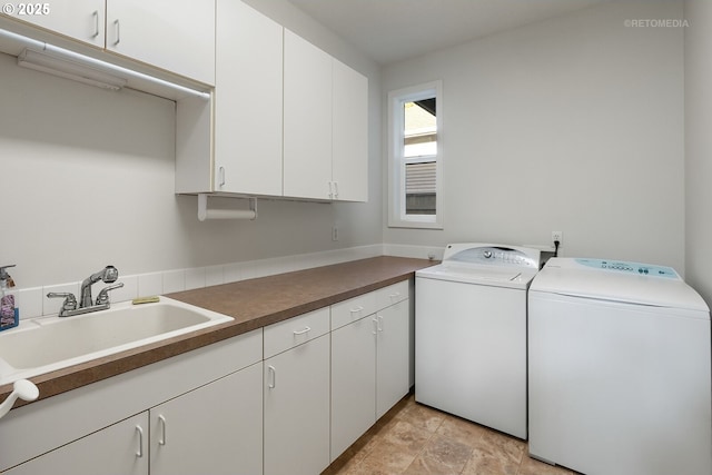 clothes washing area featuring cabinets, washer and clothes dryer, and sink