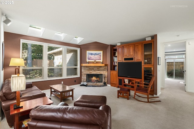 carpeted living room featuring a healthy amount of sunlight, a stone fireplace, and a skylight