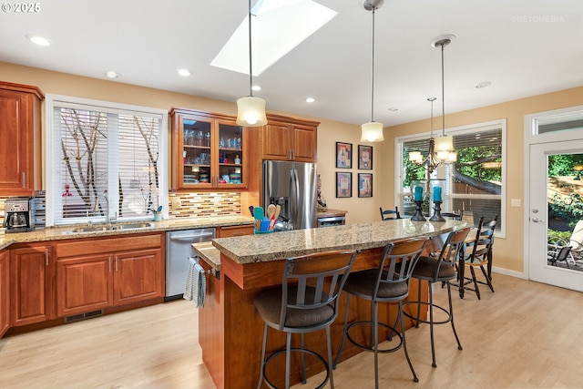 kitchen featuring sink, a breakfast bar, stainless steel appliances, a center island, and decorative light fixtures